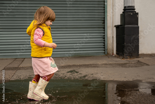 Corby, U.K., 08.09.2020. Toddler girl having fun in rain puddle, outdoor baby play activiy