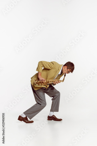 Portrait of young man in stylish yellow jacket playing saxophone isolated over white background. Jazz festival