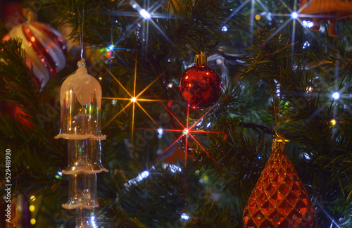 Christmas tree decoration. Glass bells. baubles and lights with star-shaped shine. Very narrow depth of field and a star-filter in front of the lens was used.