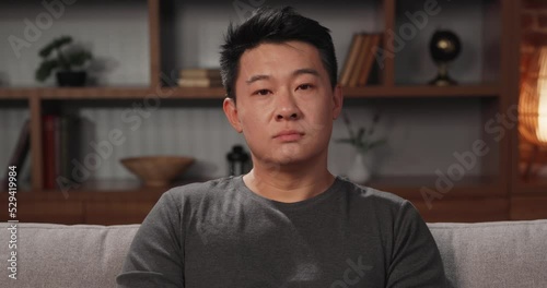 Portrait of Asian man looking at the camera at home, participating in a video conference