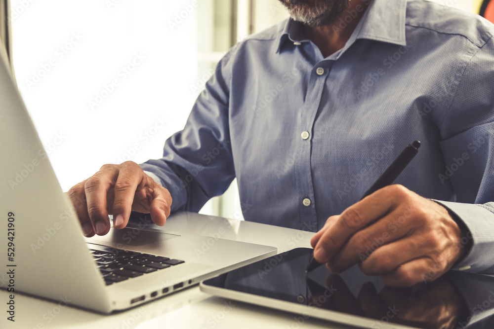 Closeup man hands using laptop and tablet. Businessman works with computer and digital pad at home