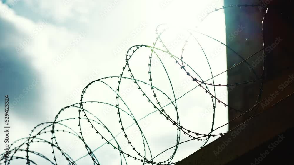 Prison barbed wire fence found at jails and correctional facilities. A fence with barbed wire against the sky. Close-up. Security systems Restricted area. Sharp razors on the concertina wire. Prison barbed wire fence found at jails and correctional facilities. A fence with barbed wire against the sky. Close-up. Security systems Restricted area. Sharp razors on the concertina wire.