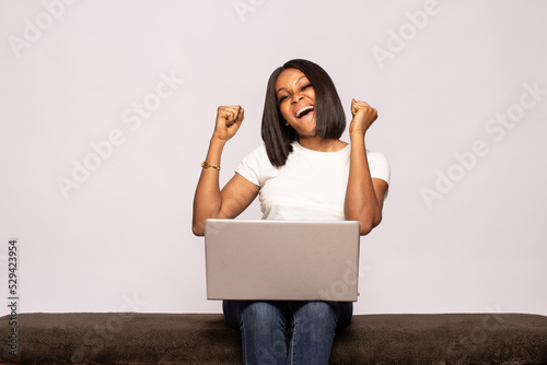 young black lady using her laptop rejoices
