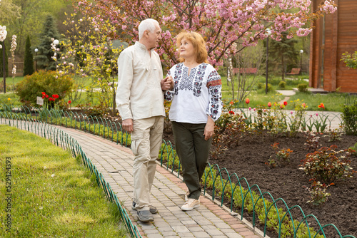 Senior couple on a walk in summer or spring nature wearing Ukrainian embroidered shirt