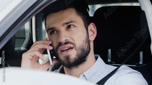 young man talking on cellphone and looking away while driving automobile. © LIGHTFIELD STUDIOS