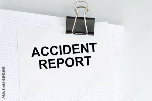 ACCIDENT REPORT text on a white card clip to a blonde on a light background