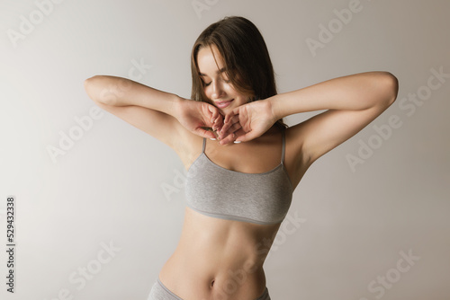 Fotografie Half-length portrait of young beautiful girl with well-kept skin wearing underwear isolated over gray background