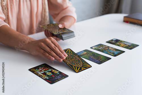 KYIV, UKRAINE - JUNE 29, 2022: partial view of fortune teller laying out tarot cards on table. photo