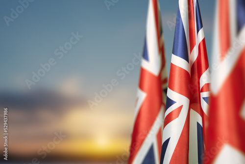 National flags of United Kingdom on a flagpole on sunset sky background. Lowered UK flags. Background with place for your text. photo