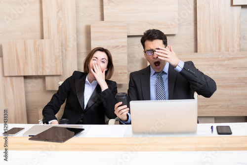 Sleepy business people yawning and going to siesta working in the office photo