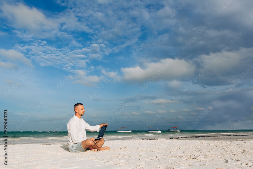 Young man using laptop computer on the beach. Relaxation Vacation Working Outdoors Beach Concept