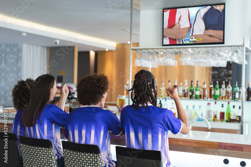 Group of diverse friends watching football match together and drinking beer the bar
