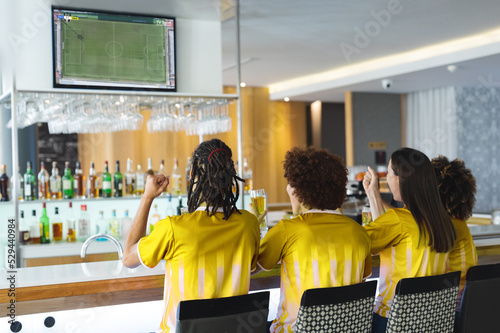 Group of friends drinking bear watching football match siting together in bar