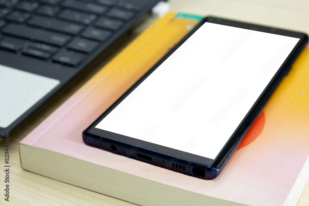 Smart phone with book and computer and notebook are on a table . Smart phone with book and computer and notebook are on a table .