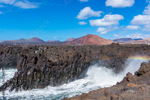 Beautiful rainbow caused by the crashing of the Ocean waves against the volcanic cliffs of Los Hervideros, Lanzarote, Canary Islands, Spain