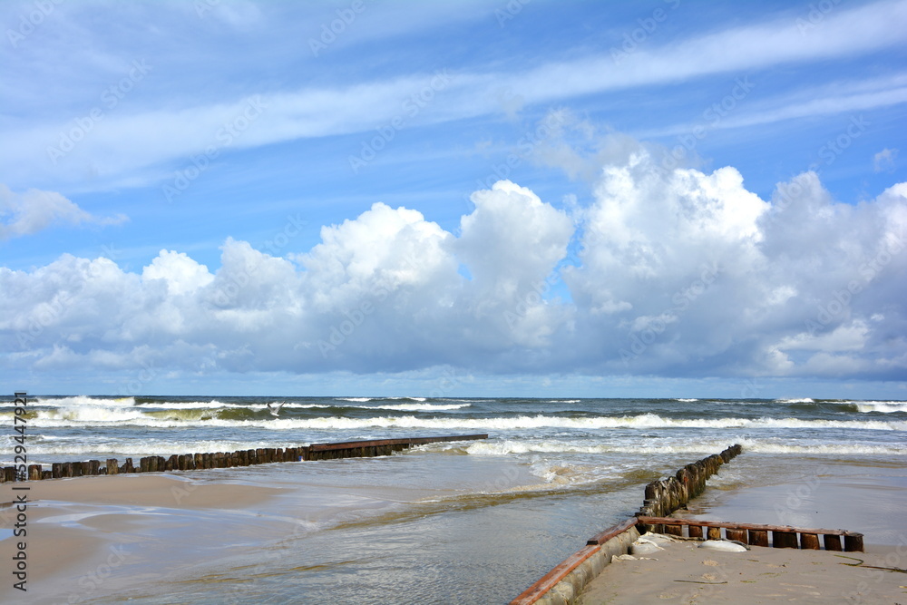 Beautiful coast of the Baltic Sea in Poland. Endless sandy beach, sea water waves. Wooden palisade by the sea. Beautiful coast of the Baltic Sea in Poland. Endless sandy beach, sea water waves. Wooden palisade by the sea.