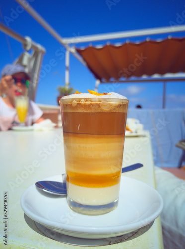 Barraquito coffee close up in a cafe garden, set against a blue sky. Shallow depth of field. photo