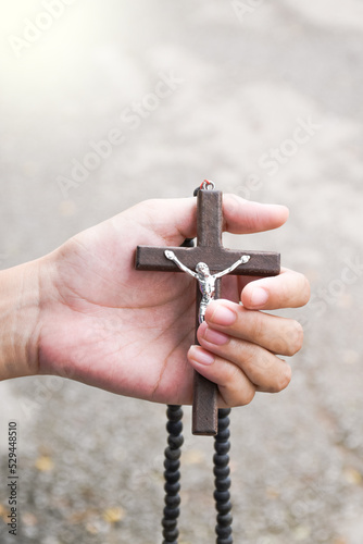 Brown wooden cross holding in hand soft and selective focus on the cross