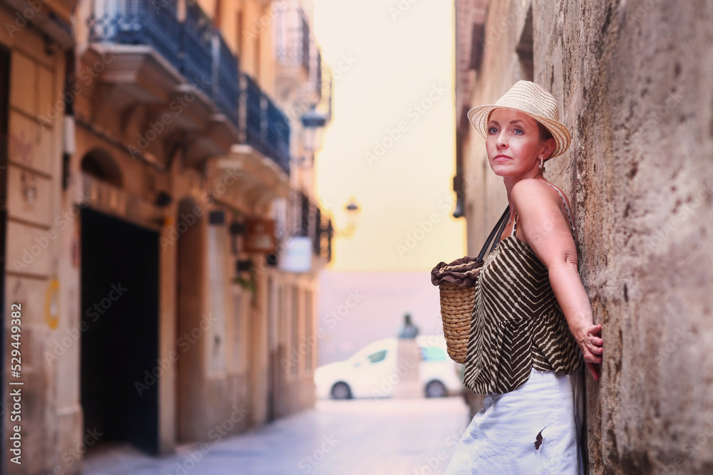 blond beautiful woman in straw hat close up portrait in Spanish old street line