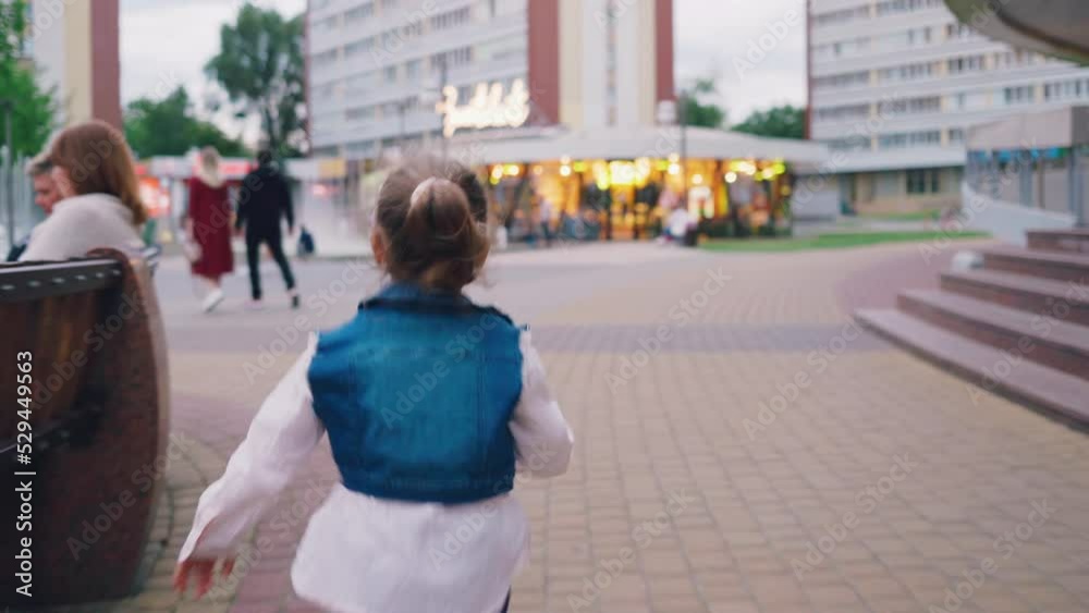 A happy little girl runs down the street to the fountain
