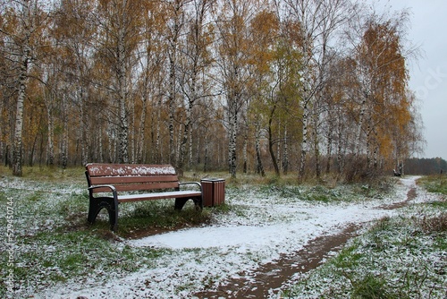 A bench in an autumn Park, dusted with snow
