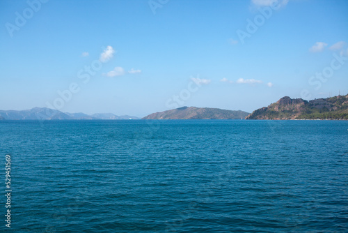 Summer seascape beautiful waves, blue sea water in sunny day. Sea bay with far hazed mountains on horizon. Fog in the mountains. © Klemenso
