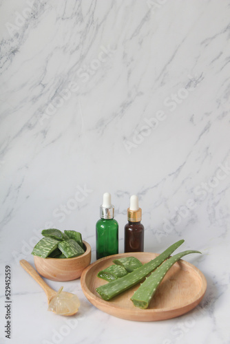 Fresh Aloe vera leaves in wooden bowl with slices and gel in wooden spoon. on white marble background. hair care and skin care concept.