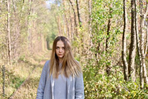 Portrait of a model girl in a gray coat. A beautiful girl with long hair and a gray coat in the forest among the trees.