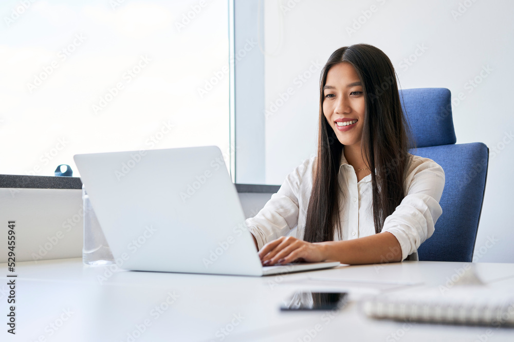 Young woman typing on laptop while working in office