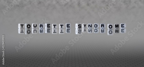 tourette syndrome word or concept represented by black and white letter cubes on a grey horizon background stretching to infinity