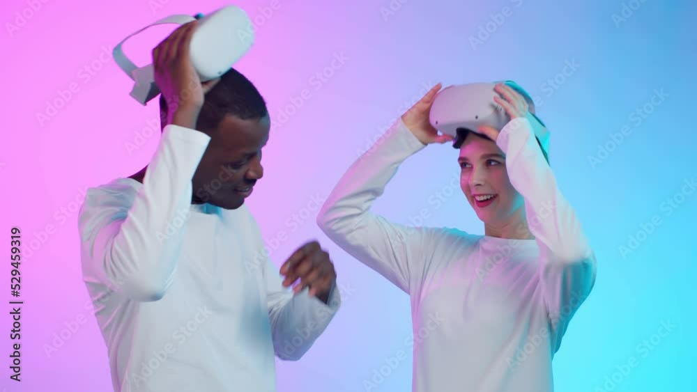 Happy African-American man and caucasian woman in white clothes remove vr goggles and laugh Happy African-American man and caucasian woman in white clothes remove vr goggles and laugh