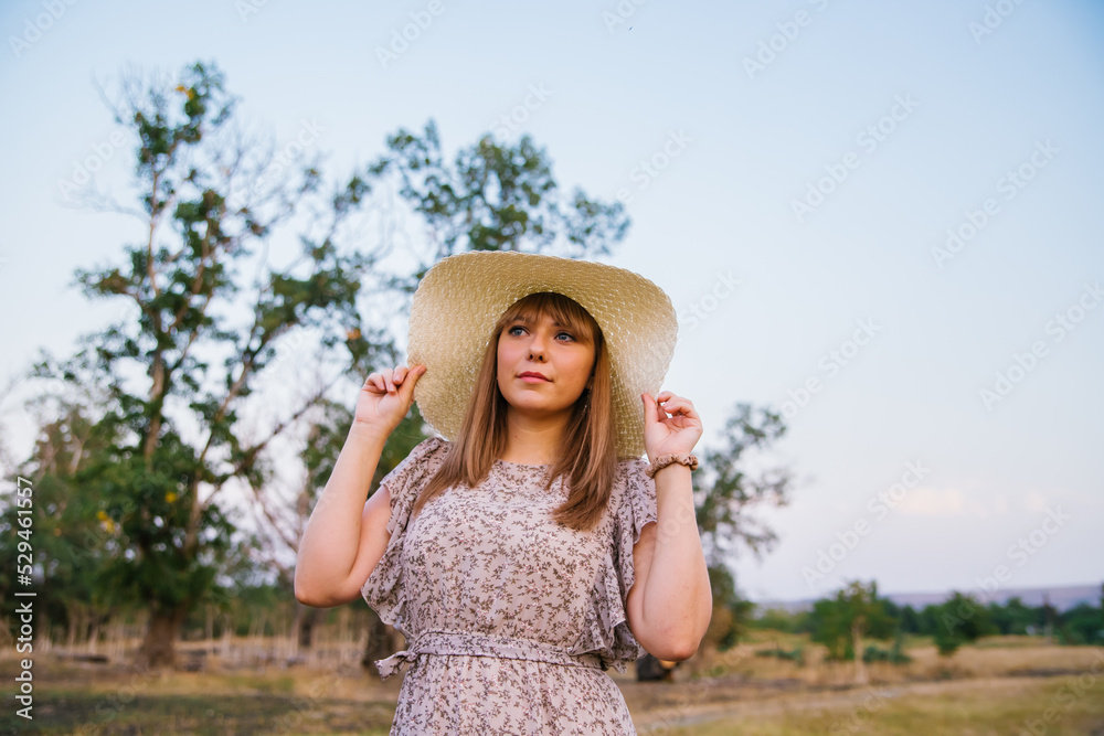 A young woman in a hat in a clearing. A walk in the park or forest. Outdoor recreation. The atmosphere of freedom and tranquility.