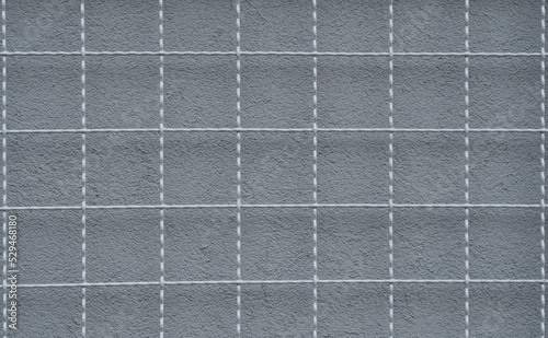 a metal grid and a gray wall behind it 2