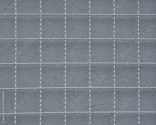 a metal grid and a gray wall behind it