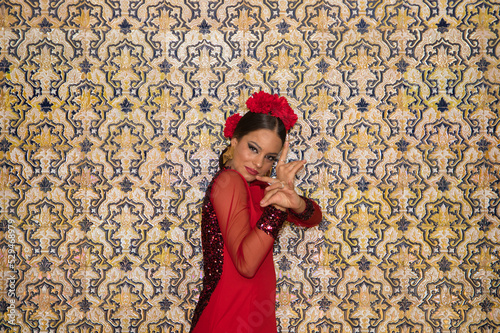 Beautiful teenage woman dancing flamenco doing different flamenco dance postures on a background of typical arabic tiles. She wears a red dress with a frill. Flamenco cultural heritage of humanity. © @skuder_photographer