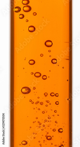 Yellow viscous liquid sunflower lecithin with bubbles in a transparent test tube on a white background