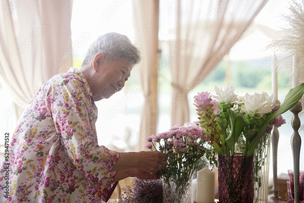 old woman decorate flower bouquet in vase on dining table old woman decorate flower bouquet in vase on dining table