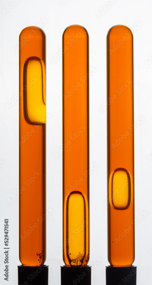 Fototapeta premium Yellow viscous liquid sunflower lecithin with bubbles in a transparent test tube on a white background