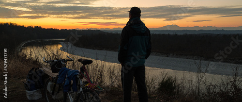 Man with mountain bike at sunset. Concept of adventure, freedom and outdoor recreation. Ticino Park and river Ticino near Castelnovate with Monte Rosa and the Alps in the background, Italy photo