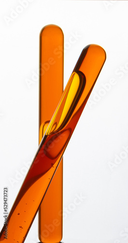 Yellow viscous liquid sunflower lecithin with bubbles in a transparent test tube on a white background