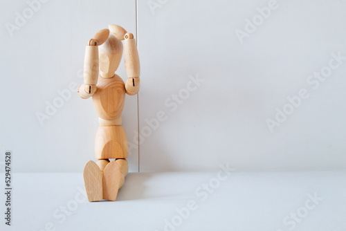 Concept of despair and regret with a wooden doll with his hands on his head	 photo