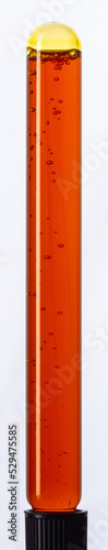 Yellow viscous liquid sunflower lecithin with bubbles in a transparent test tube on a white background