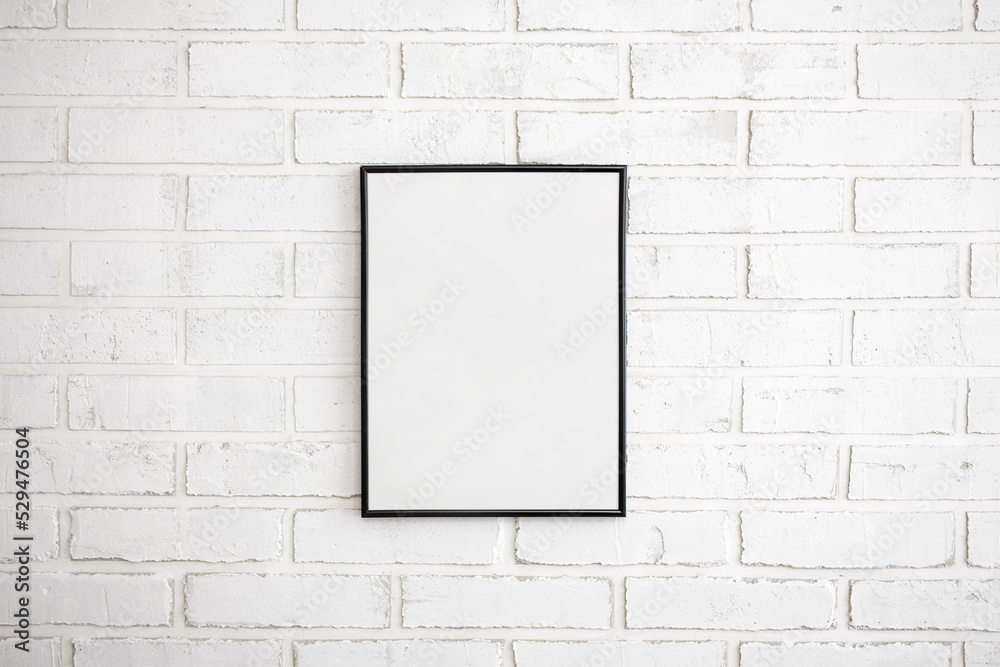 blank poster frame over white brick wall background