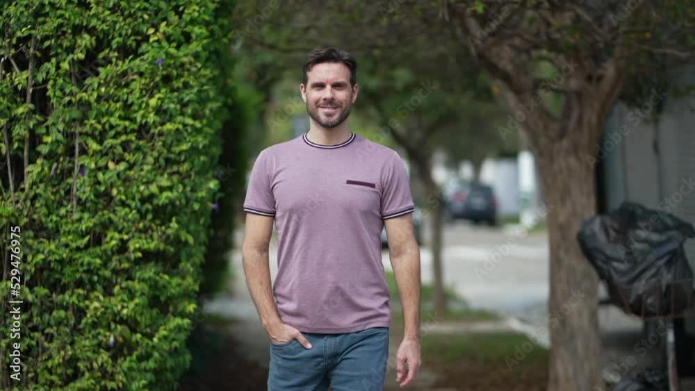 One confident man in 30s walking toward camera smiling. Handsome male person in city street sidewalk with casual clothing One confident man in 30s walking toward camera smiling. Handsome male person in city street sidewalk with casual clothing