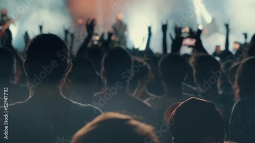 A blurry and illuminated dancing crowd at a concert. Silhouette of people at a party during the festival. People wave their hands, greeting their idol - musician, singer, rock star.