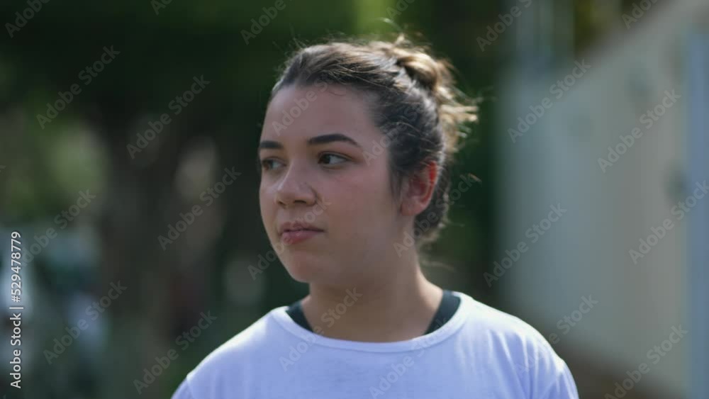 One contemplative hispanic girl walking forward in city street. Casual young latin woman in 20s in contemplation going for a walk