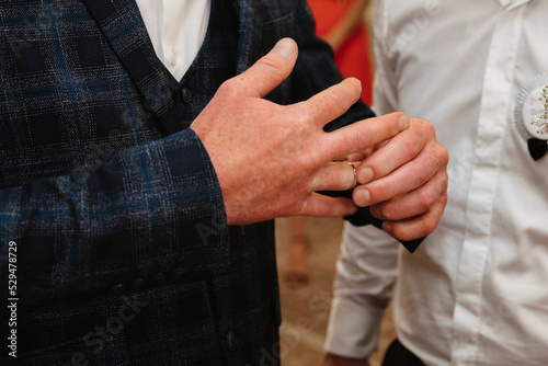 Hands of groom puts on a wedding gold ring on the wedding day