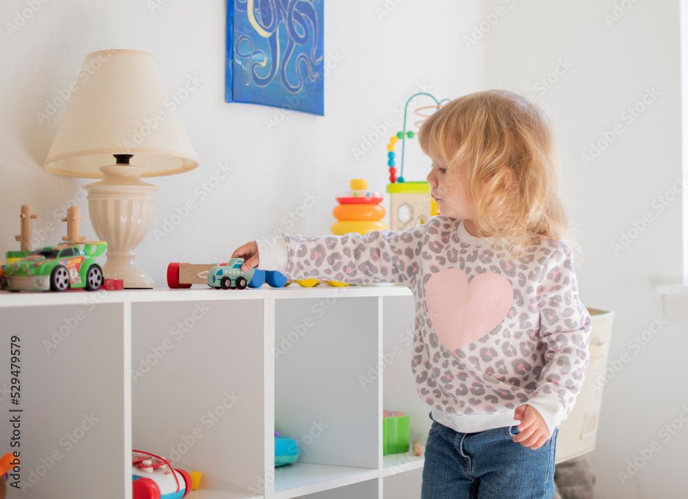 Cute caucasian blonde little girl playing in her room with the car Cute caucasian blonde little girl playing in her room with the car