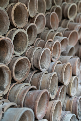 Closeup of stacks of old used weathered terra cotta flower pots in gardening shed. Empty vintage flowerpots.