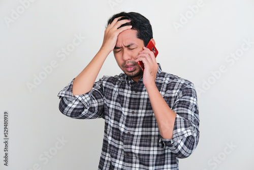 Asian man showing sad expression when answering a phone call photo